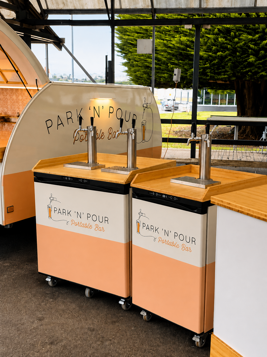 Park 'n' Pour kegerators lined up under a pavilion, twin taps and branded fronts ready to pour
